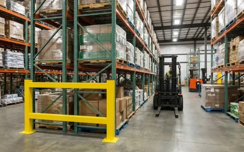 Pallet rack guard rail protecting rack ends in a busy warehouse